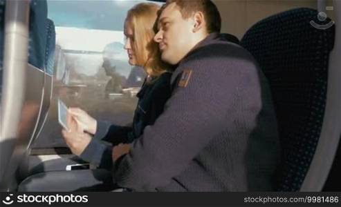Young couple taking a selfie using a tablet PC during travel on a train.