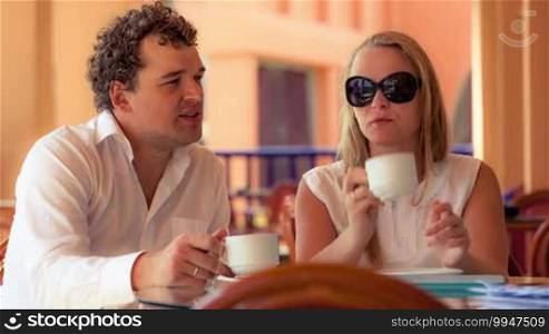 Young couple talking while having tea on a cafe terrace