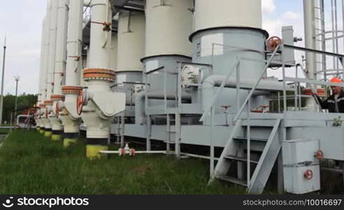 Young engineer in orange helmet returns from a walk through the territory to a gas cleaning installation and goes down stairs