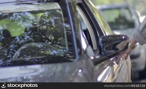 Young female driver getting in the car and fastening seat belt