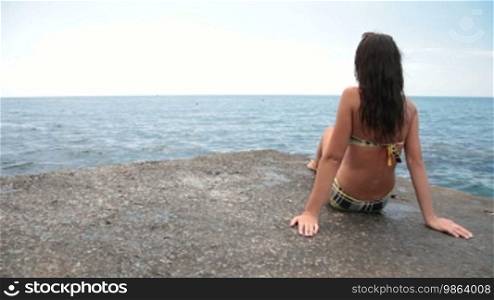 Young girl in a bikini sunbathing on the pier
