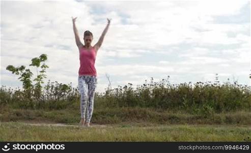 Young girl training outdoors: suppling exercises standing on hands.