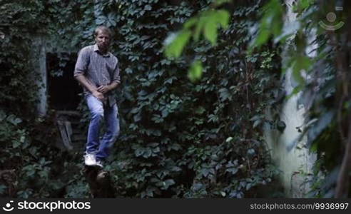 Young handsome man balancing on a dead tree and trying to make dancing moves