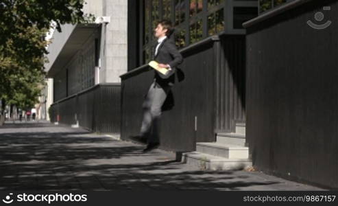 Young happy businessman exulting for joy and jumping in the street. Slow motion