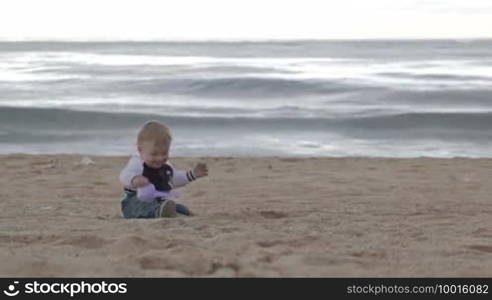 Young happy mother plays with her son on the beach.