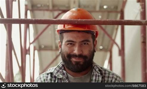 Young Latino man at work in construction site, portrait of happy manual worker smiling and looking at camera. Part 1 of 11