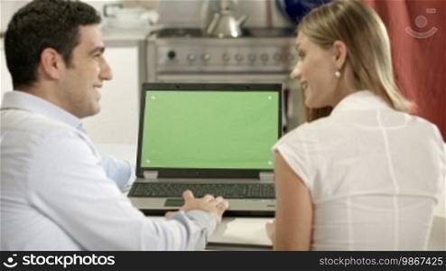 Young man and woman using laptop PC with green screen for internet and email. Dolly shot