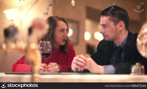 Young man and woman with a glass of wine talking while sitting at the bar counter