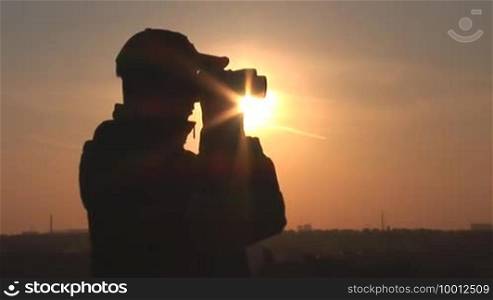 Young man looking through binoculars at sunset