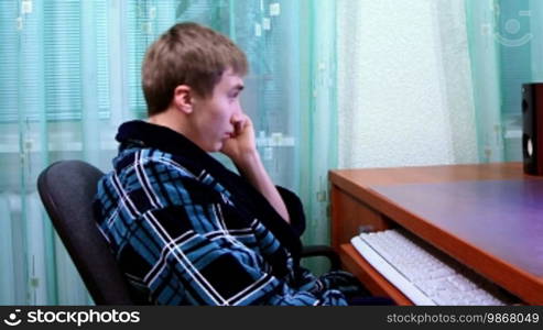 Young man talking on the phone and playing on the computer. Video shot slider