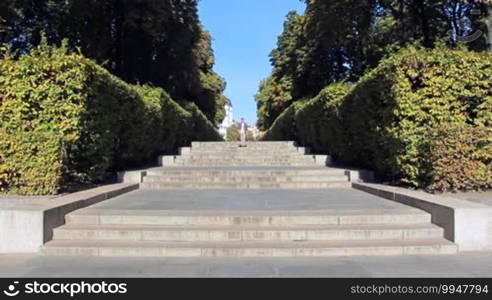 Young man walking down pretty stairs in city center through well trimmed bush