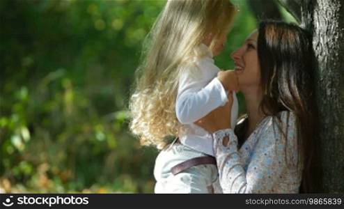 Young mother and little daughter enjoying autumn day in the park, playing