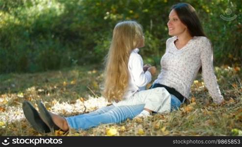 Young mother and little daughter having fun in the park