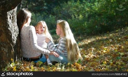 Young mother and two blond daughters enjoying a sunny day in the park