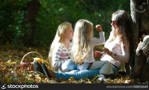 Young mother and two daughters enjoying a sunny day in the park, playing and laughing