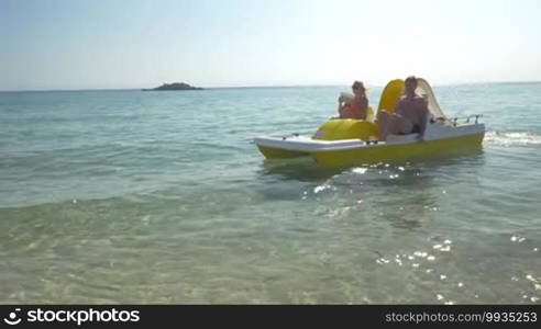 Young parents and little child having water ride in pedal boat. Mother taking selfie with pad. Family summer holidays