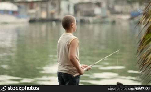 Young people and leisure activities, Hispanic boy fishing on river. Dolly shot