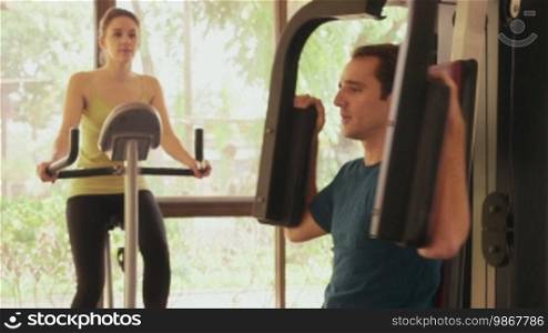 Young people and leisure, lifestyle and fun, leisure activity, man and woman on holiday. Sport athletes training, working out in fitness club with gym equipment and bike. 5 of 12