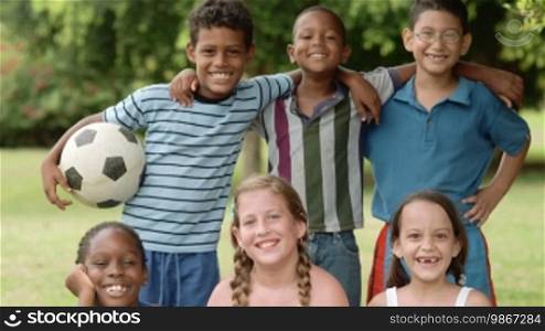 Young people and sport, portrait of six happy children with football looking at camera and smiling. Summer camp fun
