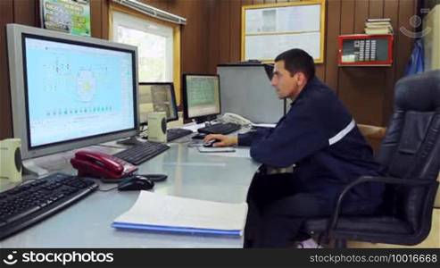 Young serious engineer working on a computer with three monitors