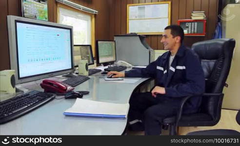 Young smiling engineer working on a computer with three monitors