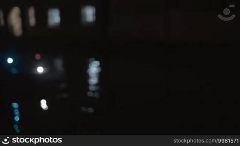 Young smiling woman in mask making selfie with smartphone by the window against water background at night. Atmosphere of Venetian carnival