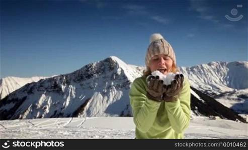 Young woman blowing on snow in Le Corbier, French Alps. Copy space