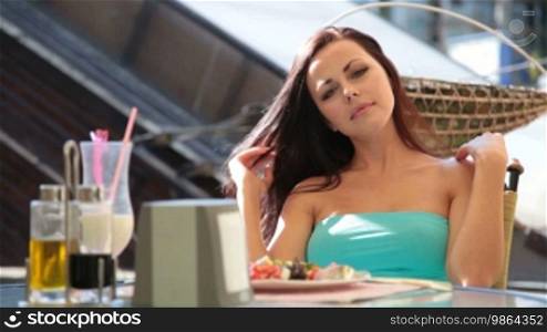 Young woman eating lunch at a relaxed outdoor restaurant