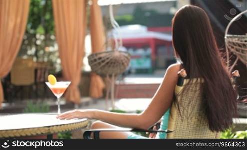 Young woman enjoying a sunny summer day with a glass of martini in hand