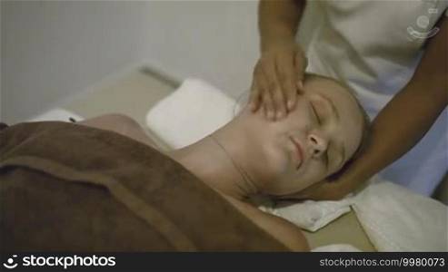 Young woman getting head and neck massage at treatment salon