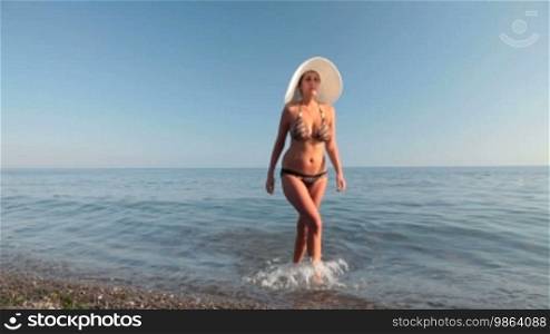 Young woman in a white hat comes out of the sea