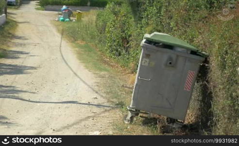 Young woman is dropping the bag with litter into a full street container.