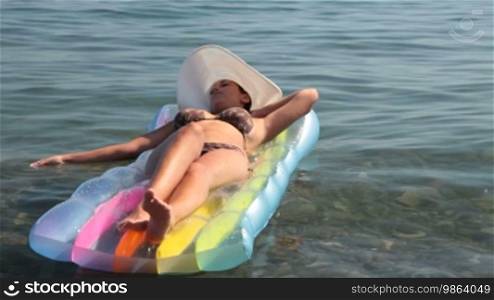 Young woman is swimming on an air bed in the sea