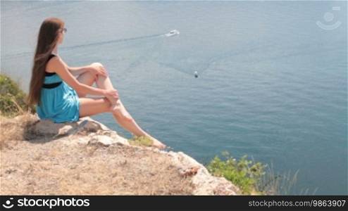 Young woman on a rock looking at the Black Sea, Balaklava, Crimea, Ukraine