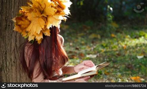 Young Woman Reading a Book in Autumn Park