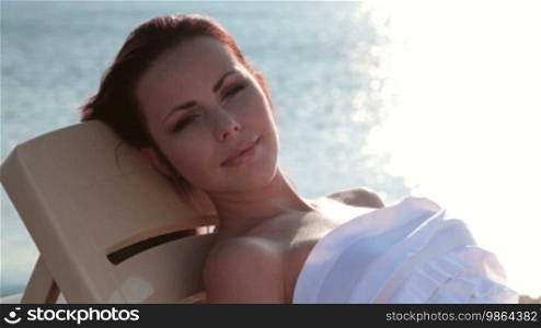 Young woman relaxing on the beach at sunset