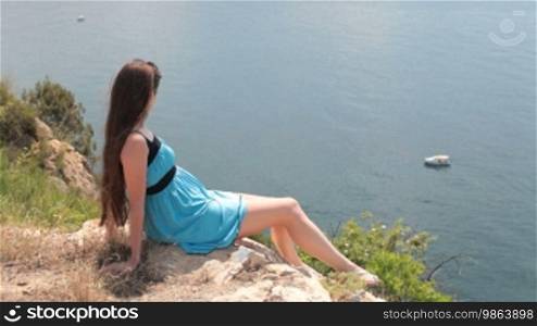 Young woman resting on a rock by the sea. Balaklava, Crimea, Ukraine