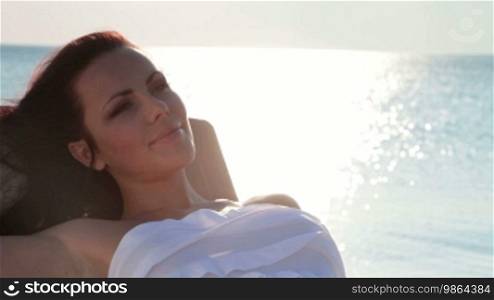 Young woman resting on the beach at sunset