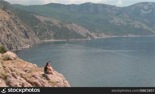 Young woman resting on the cliff near the Black Sea, Bay of Balaclava, Crimea