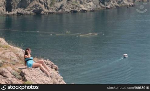 Young woman resting on the cliff near the Black Sea, Bay of Balaclava, Crimea