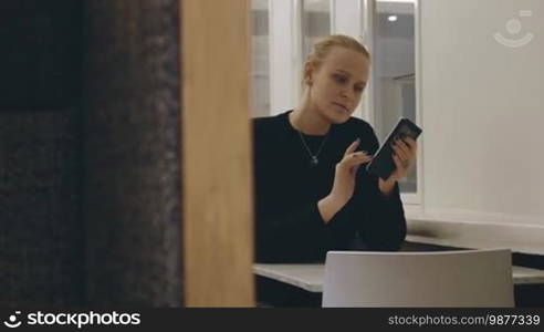 Young woman texting on cell while spending evening alone in cafe