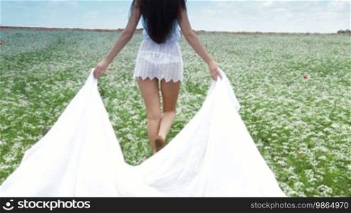 Young Woman With White Scarf Walking In a Field