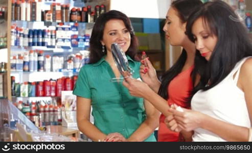 Young women shopping in cosmetics store, testing lipstick