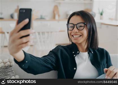 Video phone call, remote conversation. Happy mixed race woman is relaxing and chatting on smartphone. Caucasian lady enjoying time at home and smiling. Device and application using.. Video phone call. Happy mixed race woman is relaxing and chatting on smartphone.