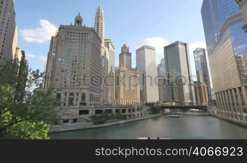 Video timelapse of Chicago downtown skyscrapers at the city center financial district in the United States of America. View of the Chicago River from the Michigan Bridge at Sunset. Clouds crossing the sky reflected on the facade glasses.