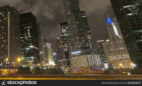 Video timelapse of Chicago downtown skyscrapers with cars driving at full speed on its streets. Awesome Chicago city center skyline at night in the United States of America. Illuminated skyscrapers of Chicago in a cloudy night. Trump Tower is one of the highest buildings in the city.