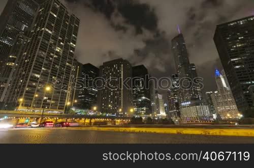 Video timelapse of Chicago downtown skyscrapers with cars driving at full speed on its streets. Awesome Chicago city center skyline at night in the United States of America. Illuminated skyscrapers of Chicago in a cloudy night. Trump Tower is one of the highest buildings in the city.
