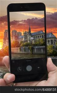 videobloger takes pictures on a smartphone sunset Notre Dame de Paris. France. Europe. videobloger takes pictures on a smartphone