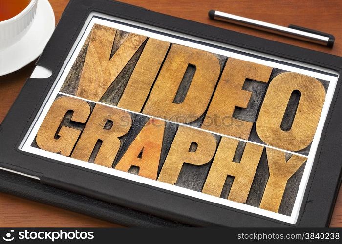 videography word abstract - text in letterpress wood type on a digital tablet with a cup of tea
