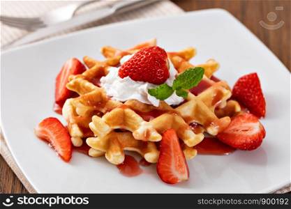 viennese waffles with strawberry and sweet syrup on a plate. viennese waffles with strawberry